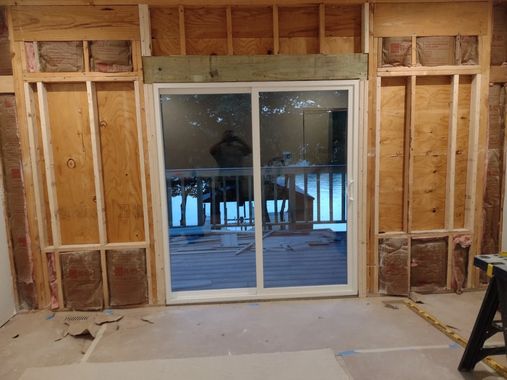 New sliding patio door in a framed wall with sheathing, deck visible outside