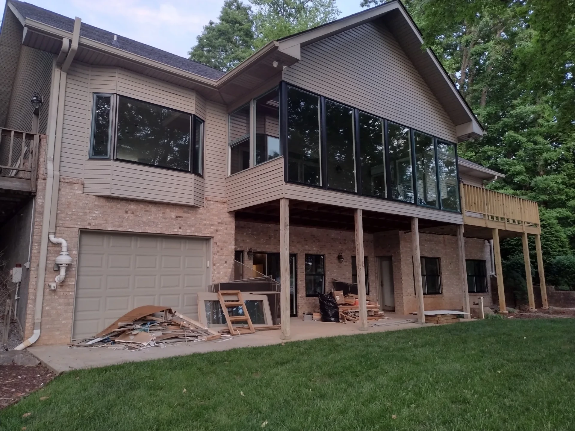 Rear of a two-story home with large new windows and a deck, work in progress